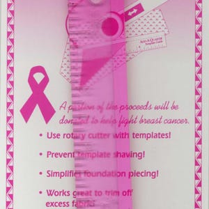 May include: Pink quilting ruler with a pink ribbon symbol and text. The ruler has measurements and a template guide. Text includes "A portion of the proceeds will be donated to help fight breast cancer."