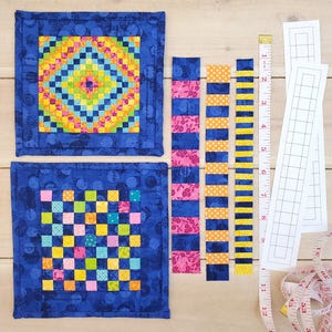Puede incluir: Dos cuadrados de tela azul con diseños de patchwork coloridos. Los cuadrados están rodeados de tiras de tela en rosa, amarillo y azul. También hay una cinta métrica y una regla en la imagen.