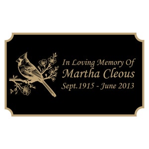 May include: A black memorial plaque with a gold border and a gold cardinal bird illustration. The plaque reads "In Loving Memory Of Martha Cleous Sept. 1915 - June 2013".