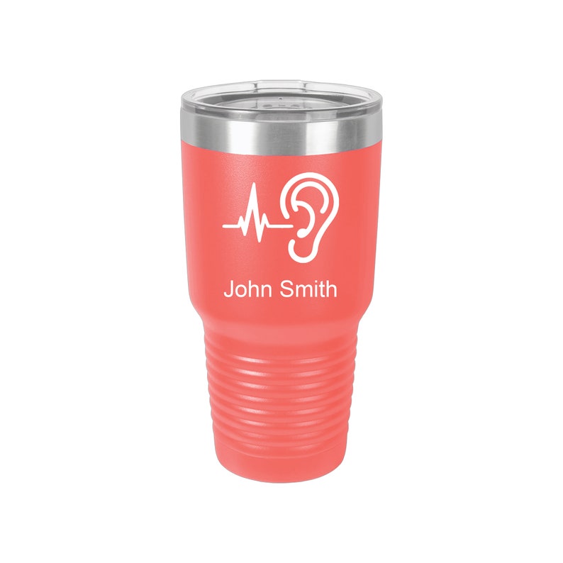 May include: Coral pink stainless steel tumbler with a white ear and heartbeat graphic and the name "John Smith" printed on the side.