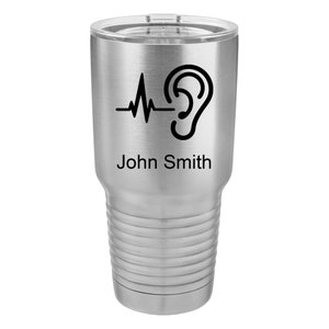 May include: A stainless steel tumbler with a black graphic of a heart beat and an ear. The tumbler has a black inscription that reads "John Smith".