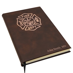 May include: A brown leather-bound journal with a gold embossed fire department logo and the text "FIRE DEPT" and a personalized inscription "John Smith, MD".