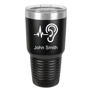 May include: Black stainless steel tumbler with a white ear and heartbeat graphic and the name "John Smith" printed on the side.