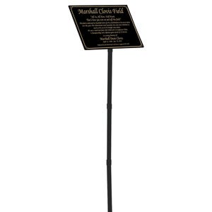 May include: A black sign with gold trim and text, mounted on a black pole. The sign reads "Marshall Clovis Field" and includes additional text about the field's dedication. The sign is likely for a sports field or memorial.