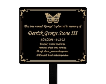 May include: Black memorial plaque with gold lettering and a butterfly design. The plaque reads "This tree named "George" is planted in memory of Derrick George Stone III 1/31/2001 - 6-12-22 Everyday in some small way, Memories of you come our way, Though absent, you are always near, Still missed, loved, and always dear."