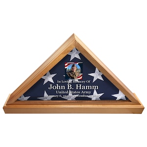 May include: Wooden flag display case with a blue and white American flag. The case contains a photo and text that reads "In Loving Memory Of John B. Hamm United States Army January 6, 1940 - December 1, 2021."