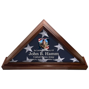 Peut inclure: Un coffret en bois pour l'exposition d'un drapeau, contenant un drapeau américain plié. Le coffret est doté d'une plaque avec le texte "In Loving Memory Of John B. Hamm United States Army January 6, 1940 December 3, 2021" et d'une petite photo d'un homme en uniforme militaire.