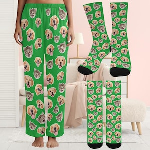 May include: Green pajama pants and socks featuring a repeating pattern of dog and cat faces. The socks have black heels and toes. The pajama pants are straight-legged.