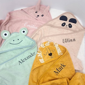 May include: Four hooded baby towels in pastel colors: pink, tan, light green, and yellow. Each towel features an animal face on the hood: a bunny, panda, frog, and lion. Names are embroidered on each towel: Emilia, Ellina, Alexander, and Mark.