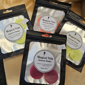 Puede incluir: Tres pequeñas bolsas de cera perfumada para usar en un difusor de fragancia para el hogar. Cada bolsa contiene tres pastillas de cera redondas y tiene una etiqueta con el texto "Magical Potts Hoover Disks" y el nombre del aroma. Los aromas son Lenor Unstoppables, Jo Malone Velvet Rose y Jo Malone Peony & Blush Suede. Cada bolsa tiene una etiqueta de precio de 2,00 €.
