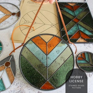 May include: A set of stained glass window hangings with geometric patterns in shades of green, orange, and white. The hangings are made of glass and metal and are suspended from leather cords. The text "Hobby License Stained Glass Pattern" is visible in the bottom right corner of the image.