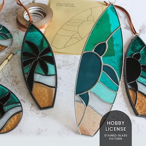 Può includere: Quattro motivi in vetro piombato di tavole da surf con disegni di tartarughe marine, palme e onde oceaniche. I motivi sono su uno sfondo bianco con il testo "Hobby License Stained Glass Pattern".