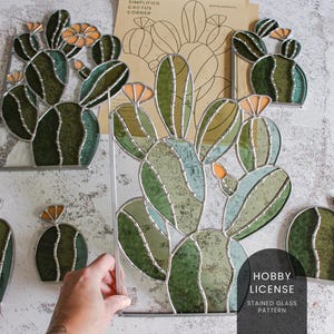 Op de afbeelding: Een glas-in-loodpatroon van een cactus met groene en oranje glazen stukken. Het patroon is gelabeld met "Hobby License Stained Glass Pattern".
