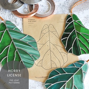May include: Stained glass fig leaf ornaments in shades of green with silver-colored metal edging. A pattern for a medium-sized fiddle fig leaf is visible, along with the text "Hobby License" and "Fig Leaf Patterns".