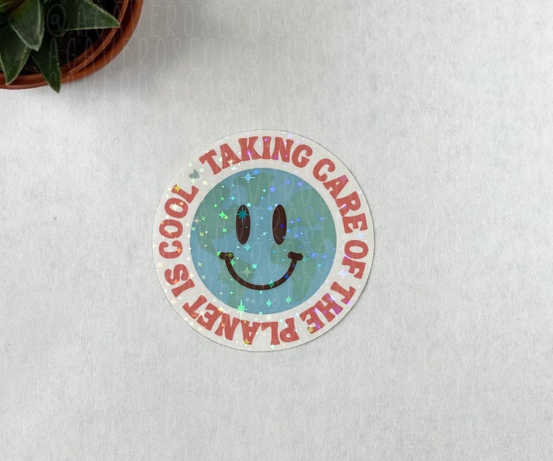 May include: A round sticker with a blue smiley face on a light blue background. The text around the smiley face reads "Taking care of the planet is cool."