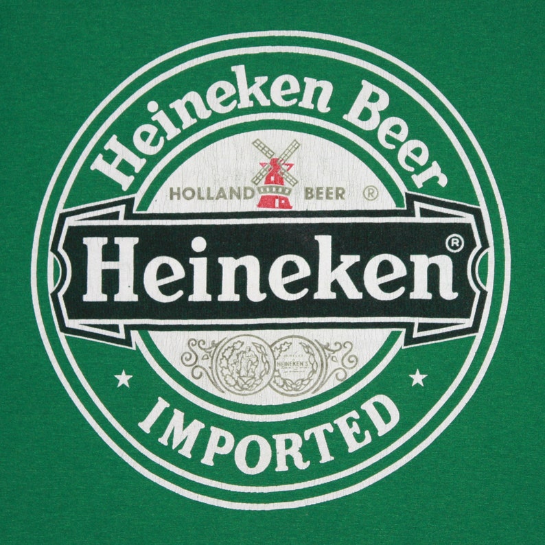 May include: A green background featuring the Heineken Beer logo. The circular logo has the word "Heineken" in white, a red windmill, and the word "IMPORTED" at the base. The text "HOLLAND BEER" is also visible.