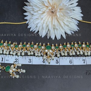 K&ouml;nnte beinhalten: Eine goldene Choker-Halskette mit gr&uuml;nen und wei&szlig;en Steinen und Perlen-Tropfen. Die Halskette ist 12,7 cm lang und wird mit passenden Ohrringen geliefert. Die Ohrringe haben gr&uuml;ne und wei&szlig;e Steine und Perlen-Tropfen.