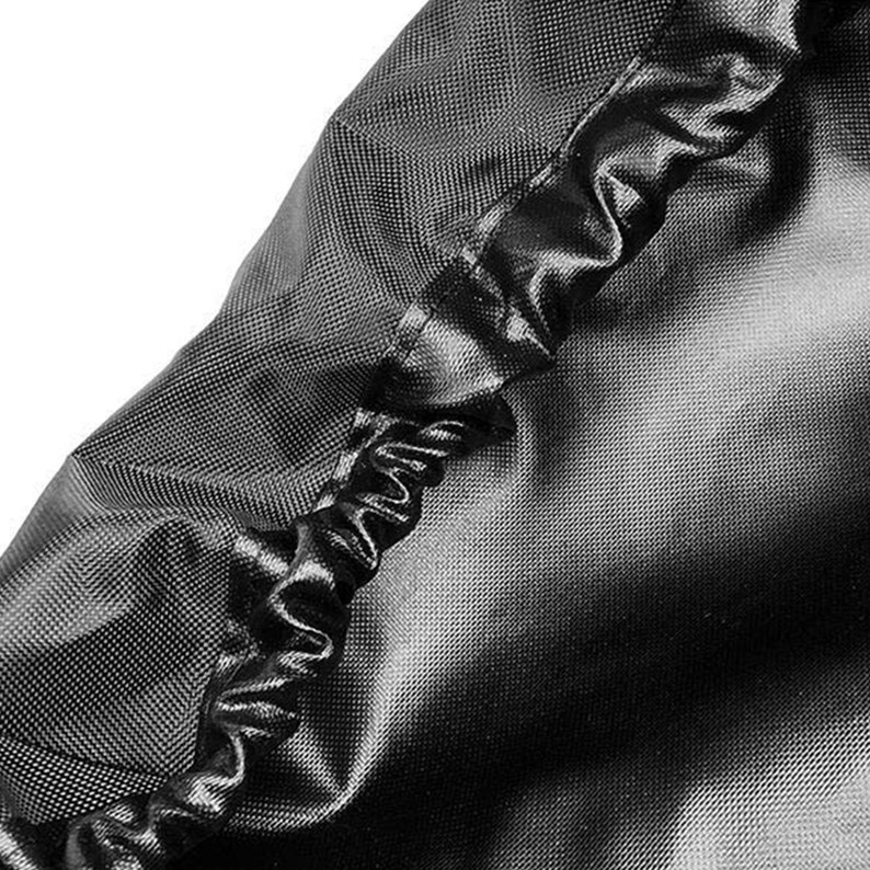 May include: Close-up of a black fabric cover with a sewn-in elastic band. The fabric has a textured, woven appearance.