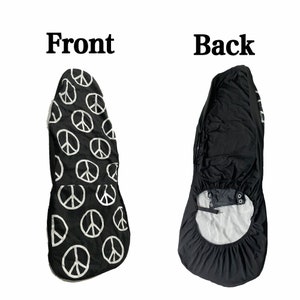 May include: Black car seat cover with a white peace sign pattern on the front and a plain black back. The cover has a strap and buckle to secure it to the seat.