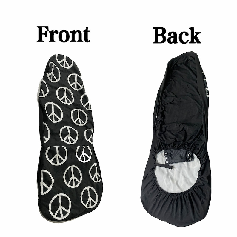 May include: Black car seat cover with a white peace sign pattern on the front and a plain black back. The cover has a strap and buckle to secure it to the seat.