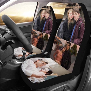 May include: A set of two black car seat covers with colorful images of couples. The images include a couple sitting on a bench, a couple standing in front of a building, and a couple lying down on a bed.