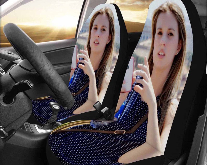 May include: Two black car seat covers with a blue and white polka dot pattern. The covers feature images of a woman holding a phone.