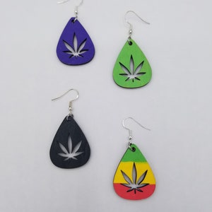 Peut inclure: Quatre paires de boucles d'oreilles pendantes de forme goutte. Les boucles d'oreilles sont en bois et présentent une découpe en forme de feuille de marijuana. Les boucles d'oreilles sont disponibles en violet, vert, noir et rouge, jaune et vert.