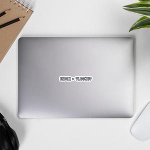 May include: A silver laptop with a white sticker that reads "INDEX > VLOOKUP" in a black font. A brown notebook with two pencils, a white mouse, a black headset, and a green plant are also visible.