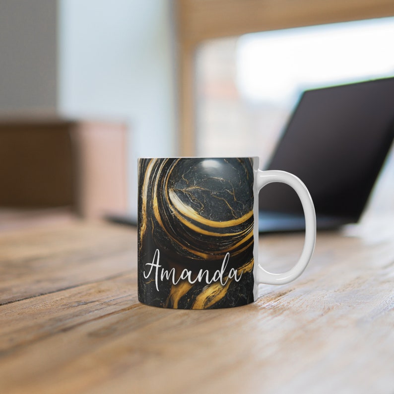 May include: White ceramic mug with a black and gold marble design. The mug has the name "Amanda" written in white cursive on the front.