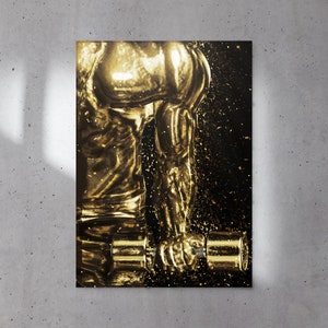 May include: A gold-toned figure of a person lifting a dumbbell. The figure is against a black background with gold glitter.