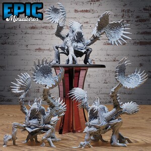Op de afbeelding: Een verzameling grijze miniatuurmonsterbeeldjes met grote, stekelige aanhangsels en open monden. De beeldjes worden tentoongesteld op een houten oppervlak met een rode en transparante standaard. De tekst "EPIC Miniatures" staat linksboven.