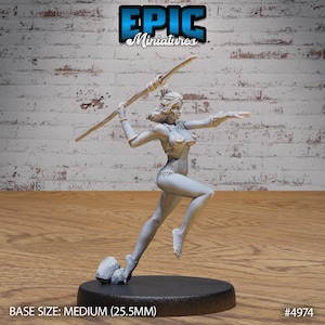 May include: A gray unpainted miniature figurine of a woman holding a spear, standing on a black base with a small rock formation. The base is labeled "BASE SIZE: MEDIUM (25.5MM)" and "#4974".