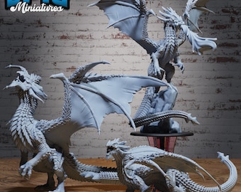 May include: A collection of gray dragon miniatures with detailed wings, scales, and poses. One dragon stands atop a rock formation, while others are positioned on a surface. The Epic Miniatures logo is visible in the upper left corner.