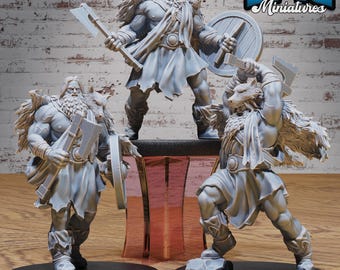 May include: A collection of gray miniature figures depicting Norse warriors. The figures include a warrior with an axe and shield, and two others with axes and hammers. The figures are on black circular bases. The logo "EPIC Miniatures" is in the upper right corner.