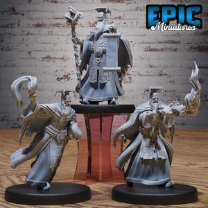 May include: Three gray miniature figures of robed characters with skull faces. One figure holds a scroll, another a staff, and the third a flame. The figures are on black bases, with the central figure on a small table. The Epic Miniatures logo is in the top right.