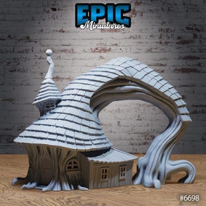 May include: A gray miniature fantasy house with a tree-like structure. The house features a detailed roof, windows, and a door. The structure includes the text "EPIC Miniatures" and the number "#6698".