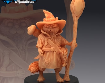 May include: A tan-coloured miniature figurine of a cat wizard, wearing a hat, robe, and holding a staff. The figurine has a detailed design, including a tail, pouches, and a belt. The base is black, and the logo "EM EPIC Miniatures" is in the top left corner.