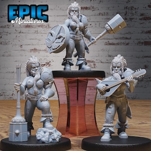 May include: Three grey painted miniature figurines of female dwarves. One dwarf is holding a large hammer, another is holding a shield, and the third is playing a lute.