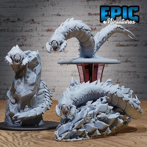 May include: Three gray, 3D printed, fantasy creature miniatures. One is a worm-like creature with a single eye, another is a worm-like creature with a single eye and a rocky exterior, and the third is a worm-like creature with a single eye and a rocky exterior, curled up on a rocky base.