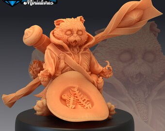May include: A miniature figurine of a cat-like creature wearing a hat and holding a staff. The creature has a large, open mouth and a surprised expression. The figurine is painted in a light brown colour.