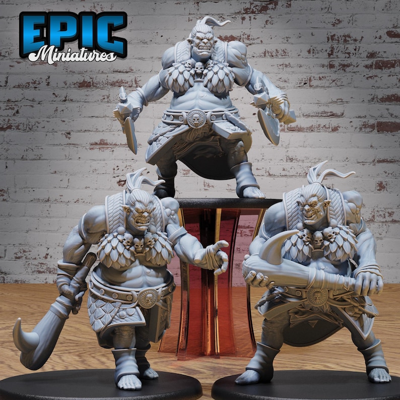May include: Three gray 3D printed miniatures of orcs, each with a different pose and holding a weapon. The orcs are wearing armor and have skulls and other decorations on their bodies. The miniatures are on a wooden surface.