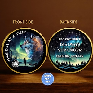 May include: A round, gold-rimmed coin with a wolf illustration and the text "ONE DAY AT A TIME" on the front. The back side reads "The comeback IS ALWAYS STRONGER than the setback" against a starry background.