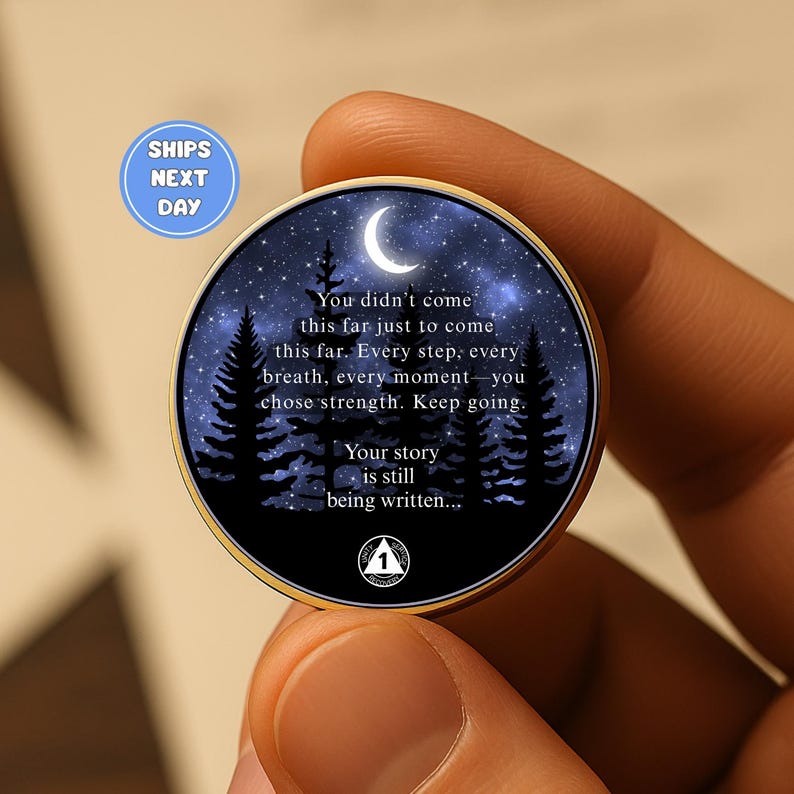 May include: A round, gold-toned coin with a night sky design featuring a crescent moon, stars, and pine trees. The coin has inspirational text: "You didn't come this far just to come this far... Your story is still being written..."