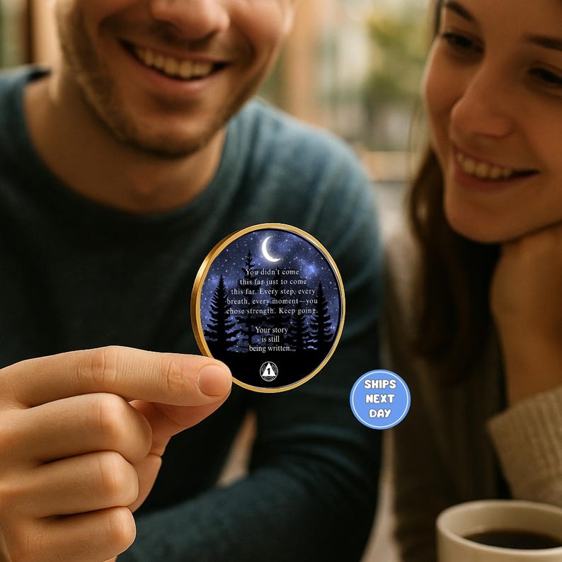 May include: A round, gold-rimmed coin featuring a night sky design with a crescent moon and trees. The coin has inspirational text: "You didn't come this far... Keep going. Your story is still being written."