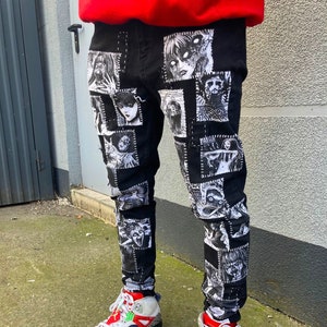 May include: Black jeans with a patchwork design featuring black and white illustrations of faces and figures. The jeans are paired with white high-top sneakers with red accents.