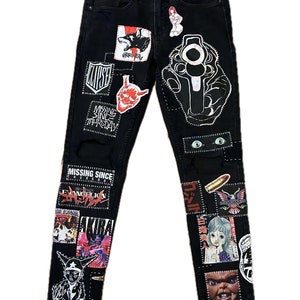 Puede incluir: Vaqueros negros de denim con varios parches y diseños, incluyendo una pistola, un demonio, un lobo y el texto "MISSING SINCE THURSDAY".