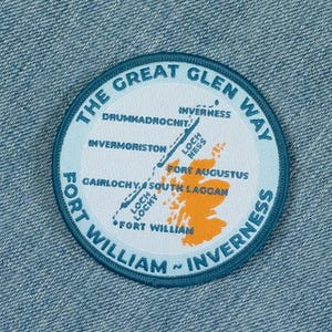 May include: A circular embroidered patch featuring a map of The Great Glen Way in Scotland. The design includes the text THE GREAT GLEN WAY, FORT WILLIAM, and INVERNESS, with locations like Loch Ness and Fort Augustus in blue and orange.