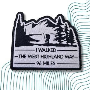 May include: Black and white embroidered patch featuring a mountain scene and a hiker. The text reads "I walked the West Highland Way - 96 miles".
