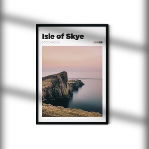 May include: A framed print of a scenic landscape featuring a rocky cliff overlooking a body of water. The sky is a soft pink and purple, and the water is a deep blue. The print is titled "Isle of Skye, Scotland UK".