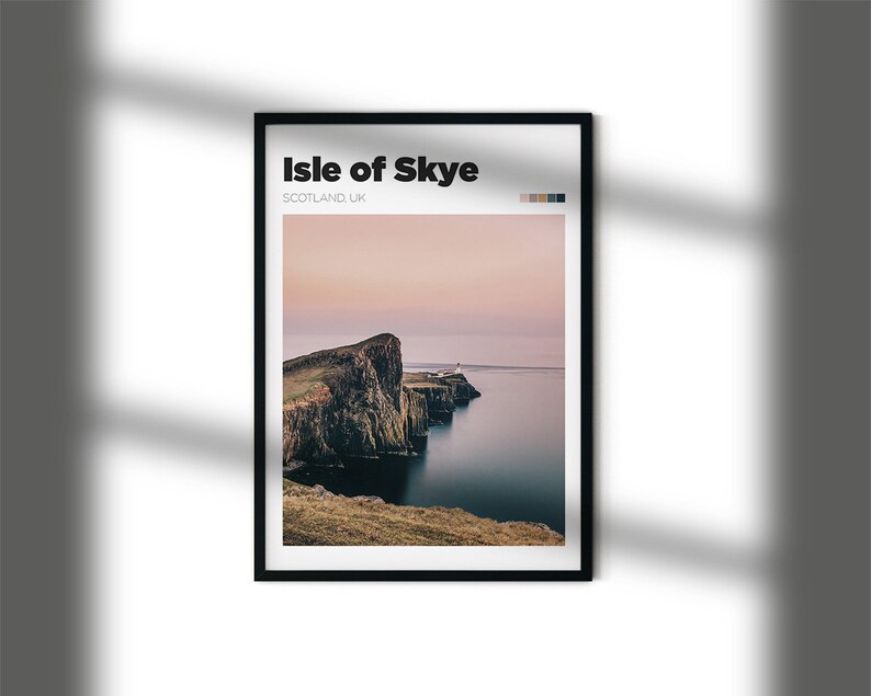 May include: A framed print of a scenic landscape featuring a rocky cliff overlooking a body of water. The sky is a soft pink and purple, and the water is a deep blue. The print is titled "Isle of Skye, Scotland UK".